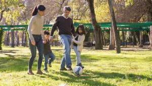 A family plays soccer together in a sunny park, enjoying quality time outdoors.